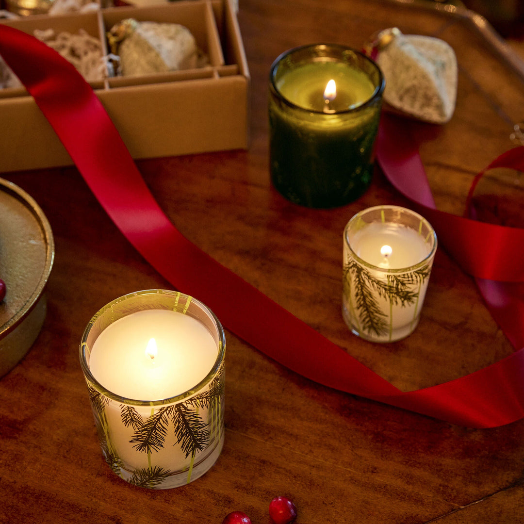 Frazier Fir Pine Needle Votive Candle by Thymes, showcasing a scented candle in a glass holder with pine needle design.