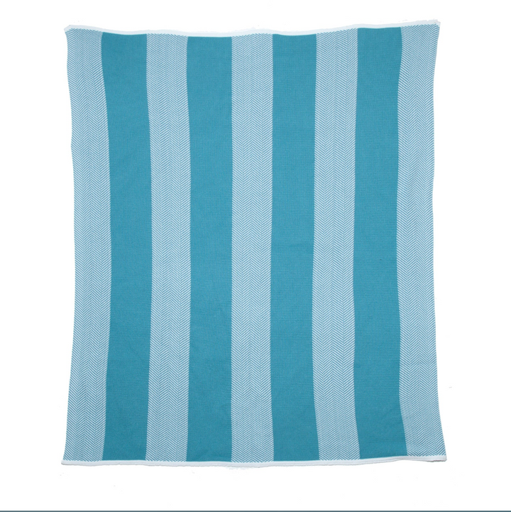 In2Green outdoor herringbone stripe throw blanket with blue, beige, and white woven pattern on a cozy outdoor setting.