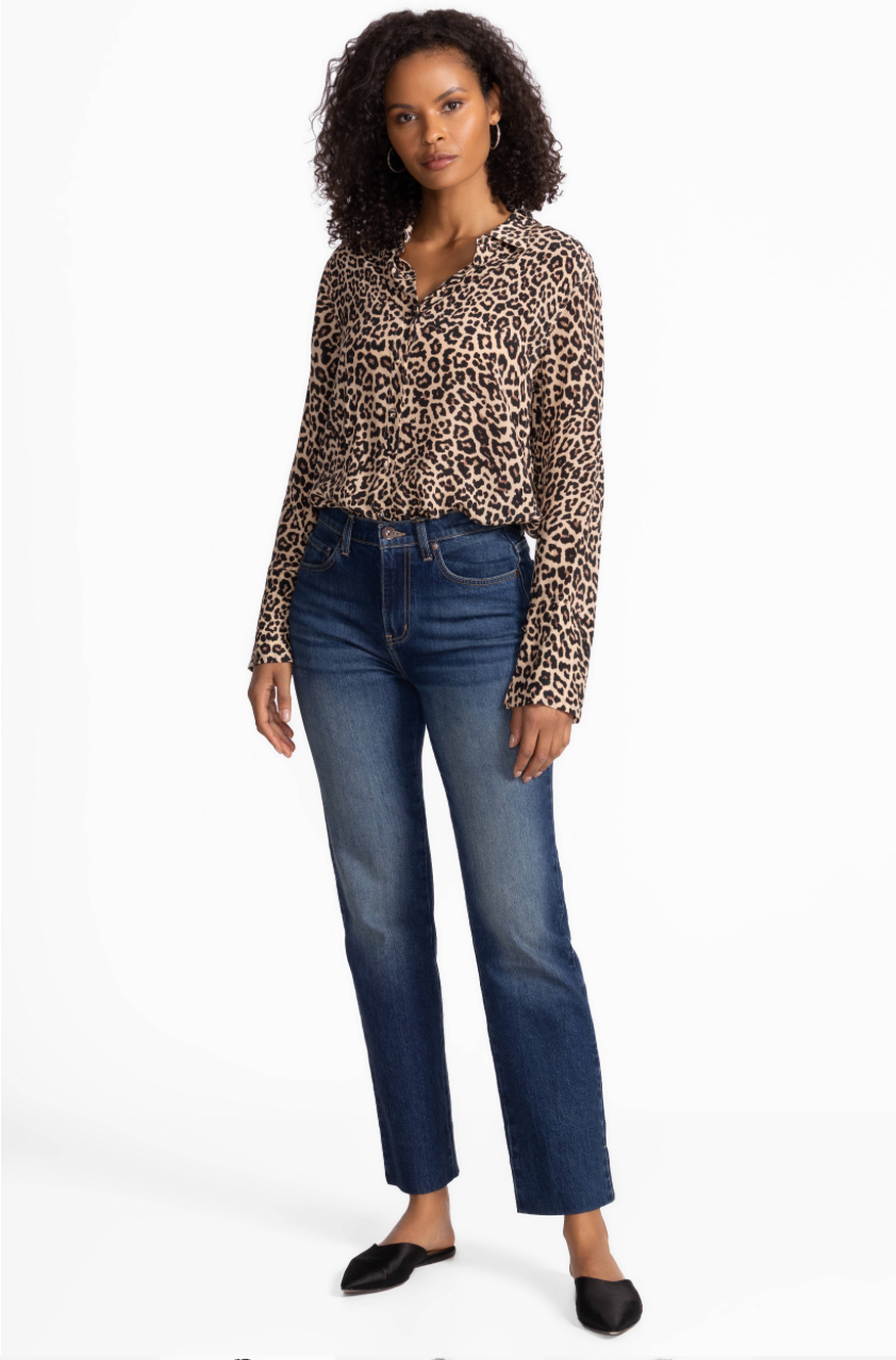 Woman wearing a leopard print top and blue jeans on a white background