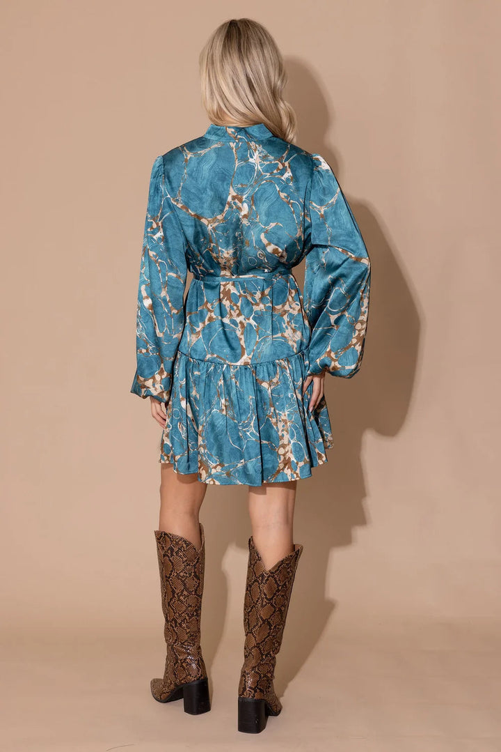 Alden Adair Adele Riverstone Dress displayed on a hanger, featuring a floral pattern and flowing fabric in natural light.