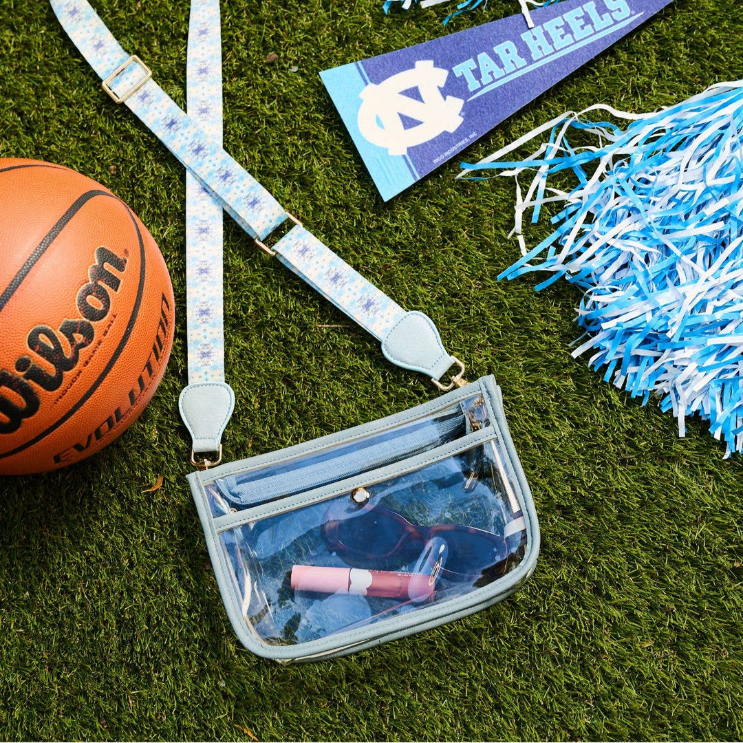 Clear stadium bag accessory by Laura Park Designs showing transparent material with black trim and adjustable strap.