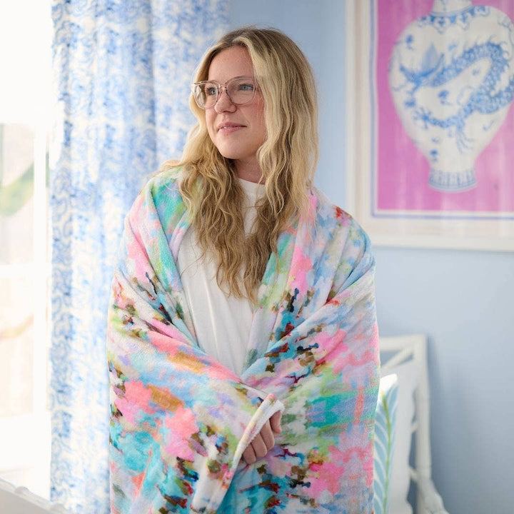 Laura Park Designs Brooks Avenue Fleece Blanket shown spread out on a cozy home setting, featuring soft, plush fabric in neutral tones.