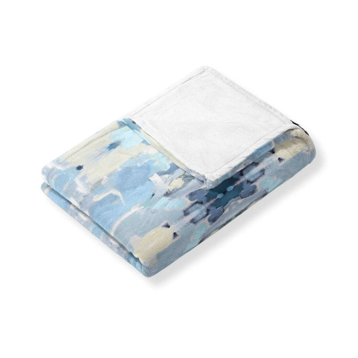 Soft Ocean Breeze fleece blanket by Laura Park Designs shown draped on a cozy sofa, highlighting its plush texture and calming blue tones.