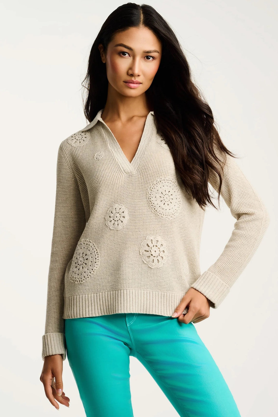 beige crochet v-neck sweater with aqua teal pants on cream background