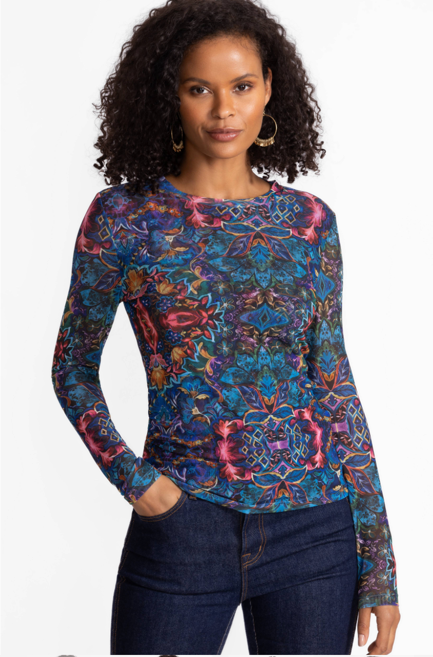 Woman wearing a colorful patterned long-sleeve top against a white background