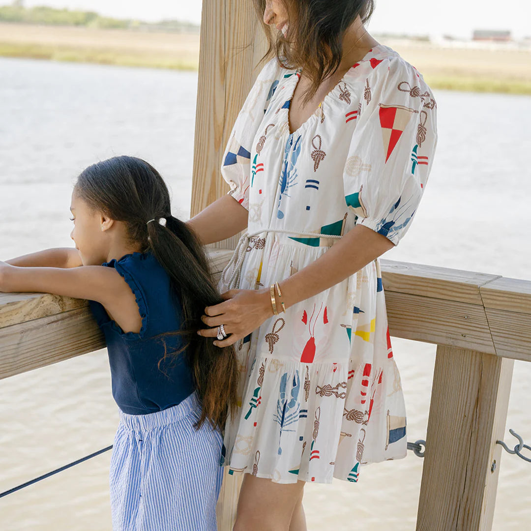 Pink Chicken Emily Dress displayed on a hanger, featuring a colorful floral pattern and lightweight fabric for a stylish, comfortable look.