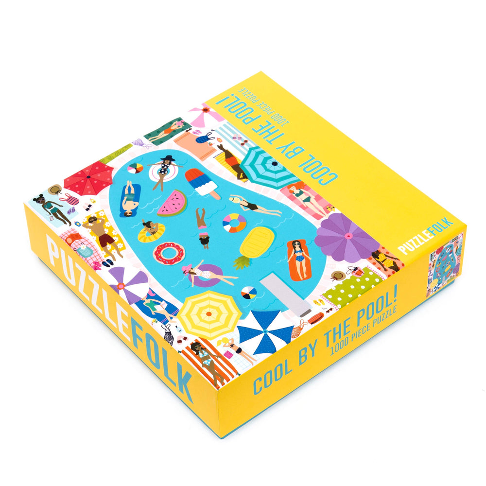 Colorful puzzle gift box labeled "Cool By The Pool" from Puzzlefolk, featuring vibrant poolside and summer-themed illustrations.