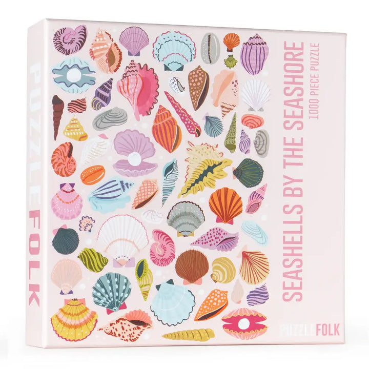 Colorful seashells by the seashore puzzle by Puzzlefolk, featuring a variety of shells arranged on a sandy background.
