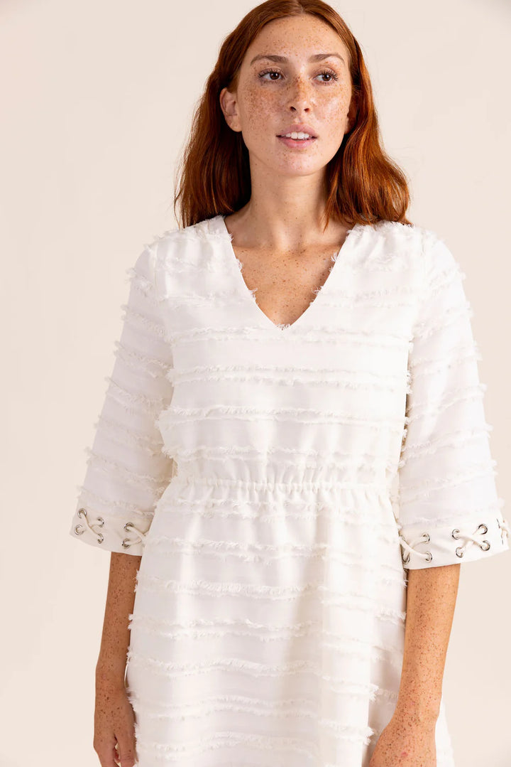 Sedge Linda Fringe Dress with flowing fabric and decorative fringe details, shown on a hanger against a neutral background.