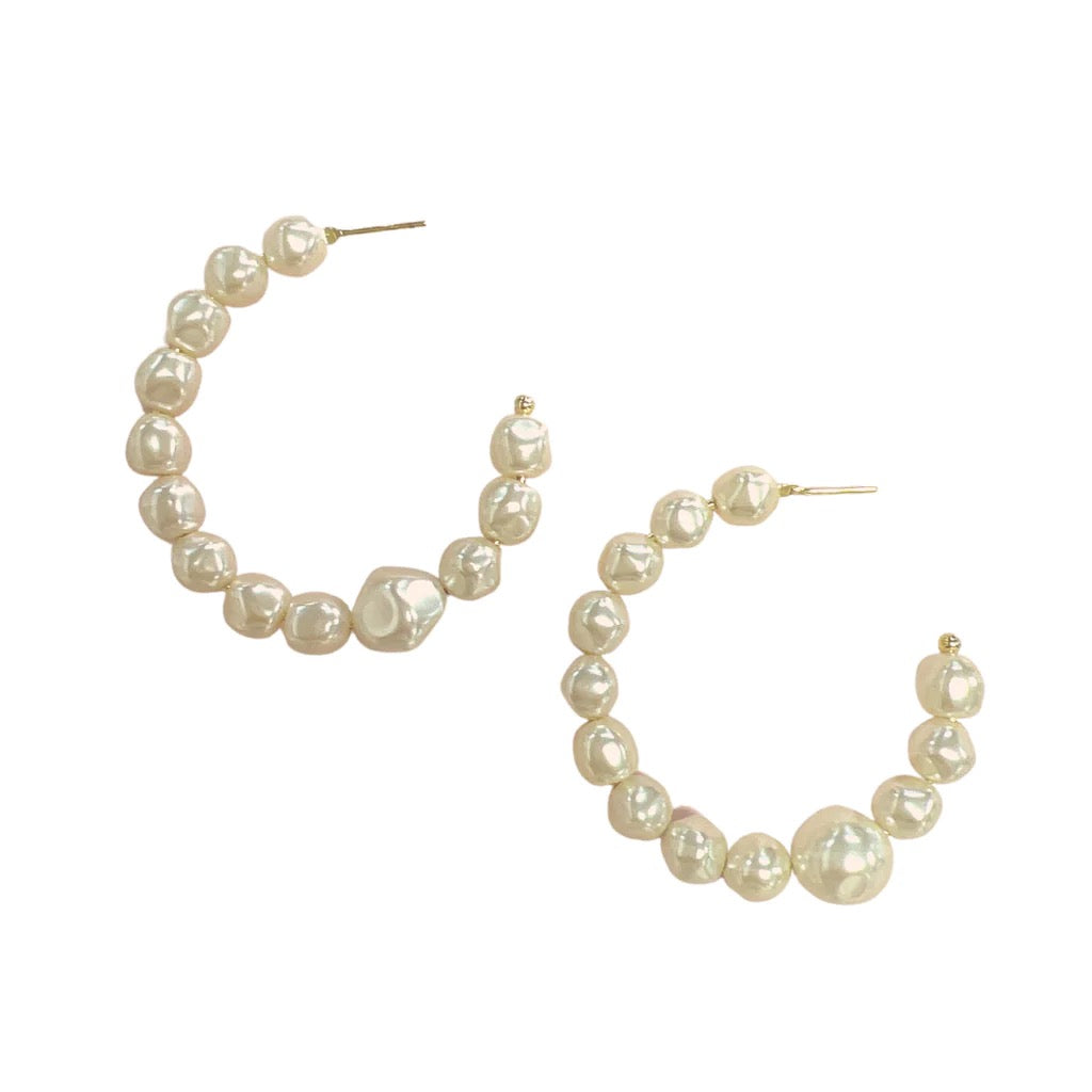 Sheila Fajl Nubia Hoop accessories, gold-toned hoop earrings with intricate design, visible on a model's ear.