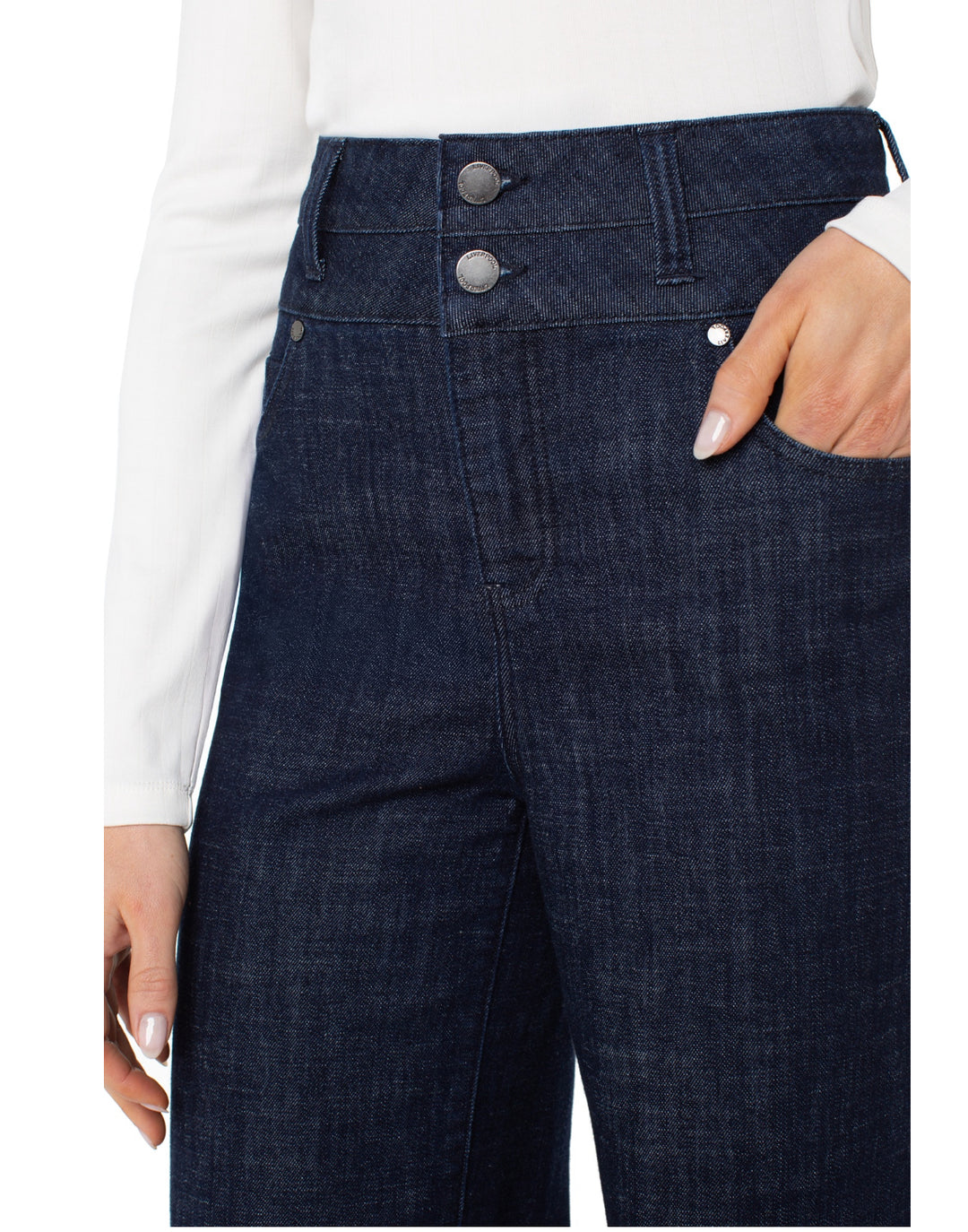 Dark blue jeans with button details worn by a person on a white background