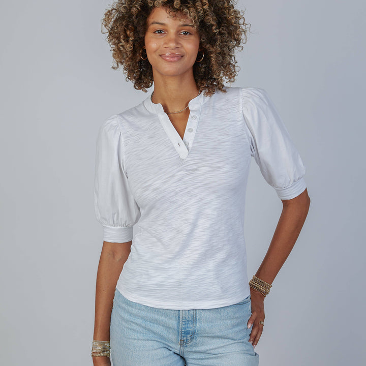 Woman wearing a white short-sleeve shirt and blue jeans against a gray background