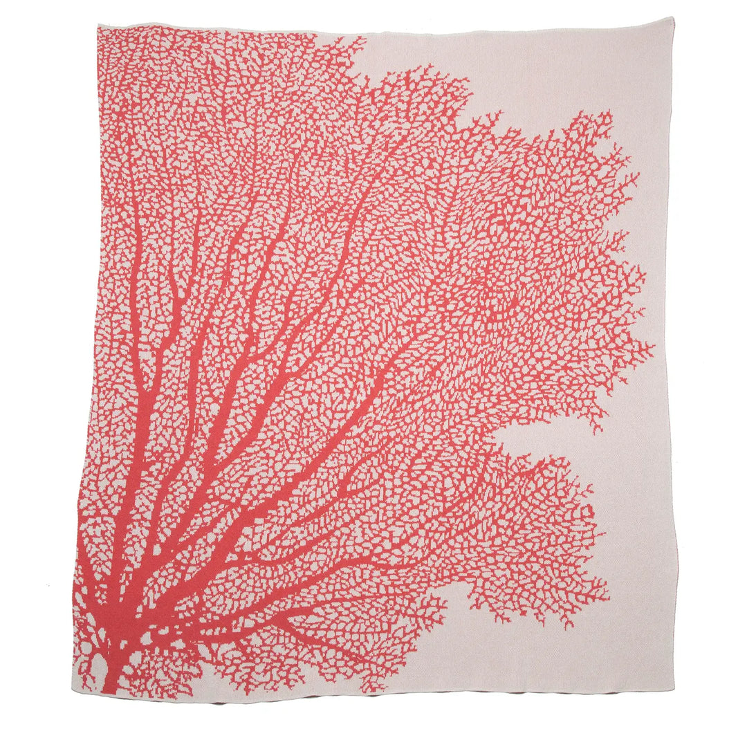In2Green coral throw blanket draped over a cozy armchair, soft textured home decor accent for living room or bedroom.